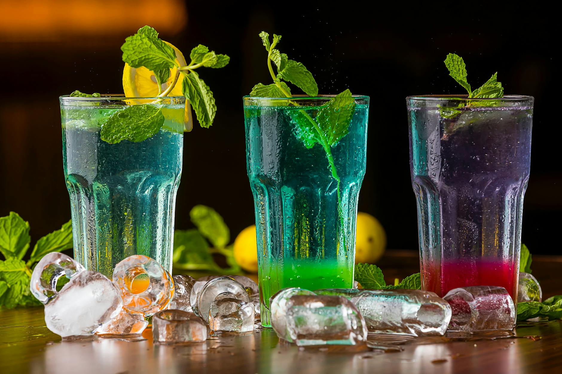 Vibrant mocktails garnished with mint and ice cubes, perfect for a refreshing drink.