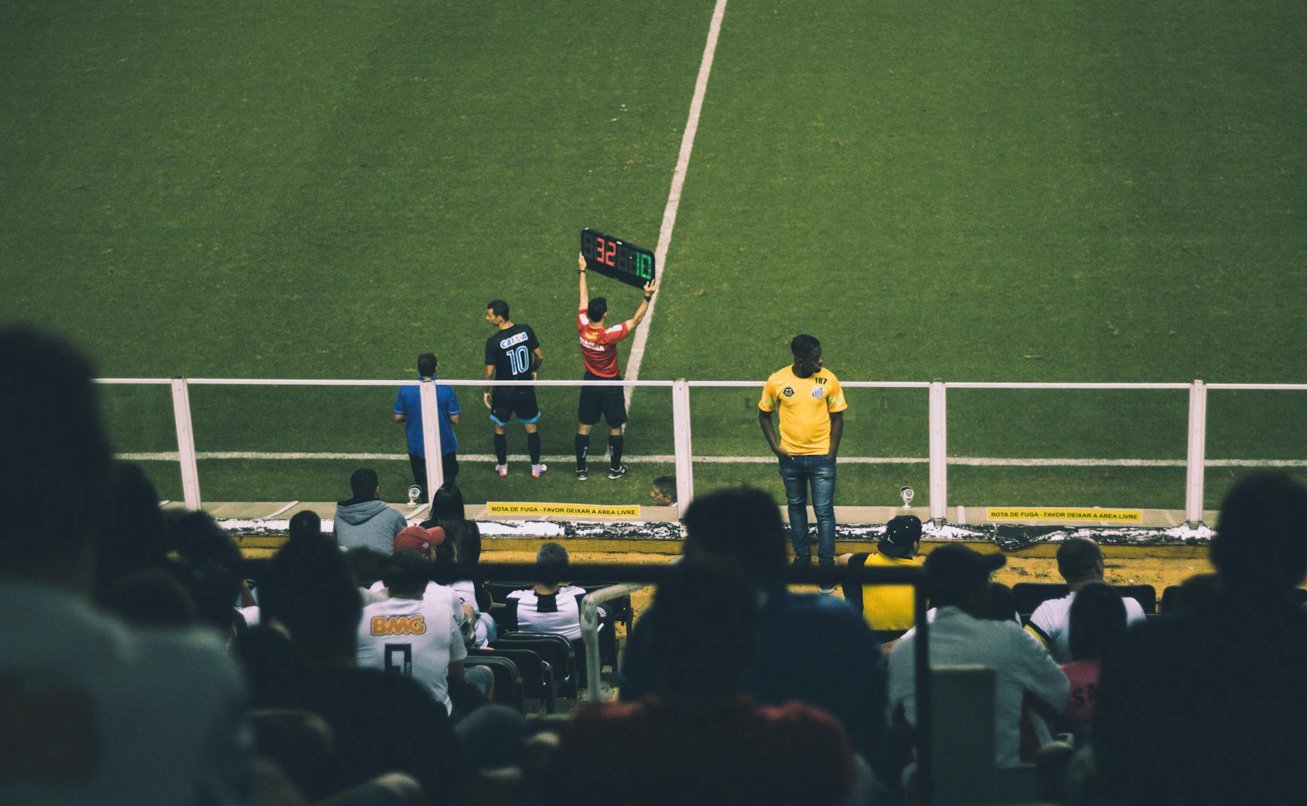 Soccer player substitution during a match at a stadium with an engaged audience.
