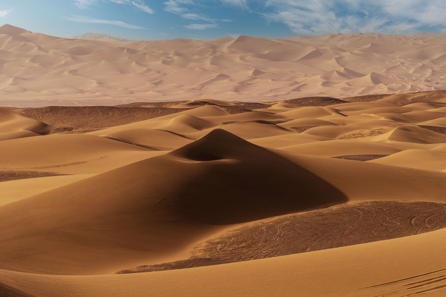 Stunning view of endless sand dunes under a bright blue sky in a pristine desert setting.