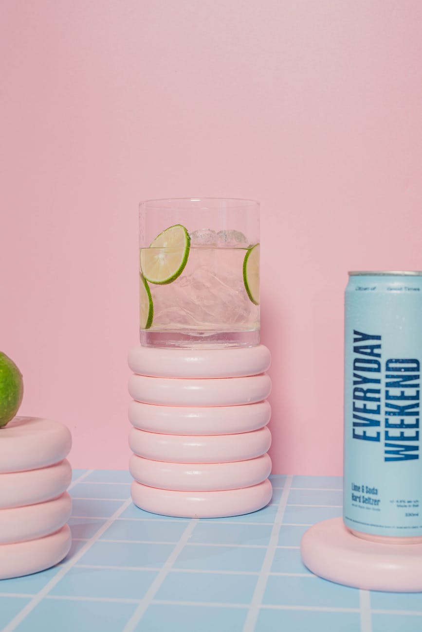 Chilled lime drink with a can and decorative elements on a pink backdrop, perfect for summer vibes.