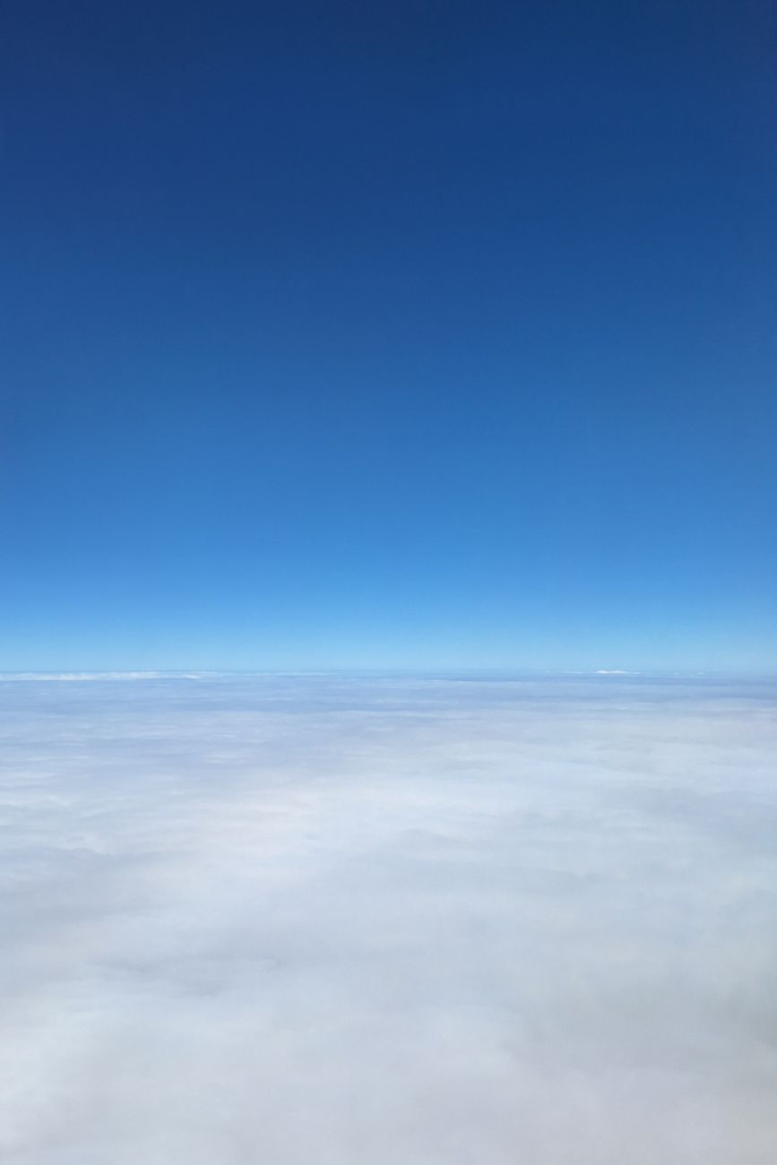 A serene view of a clear blue sky above a blanket of white clouds.