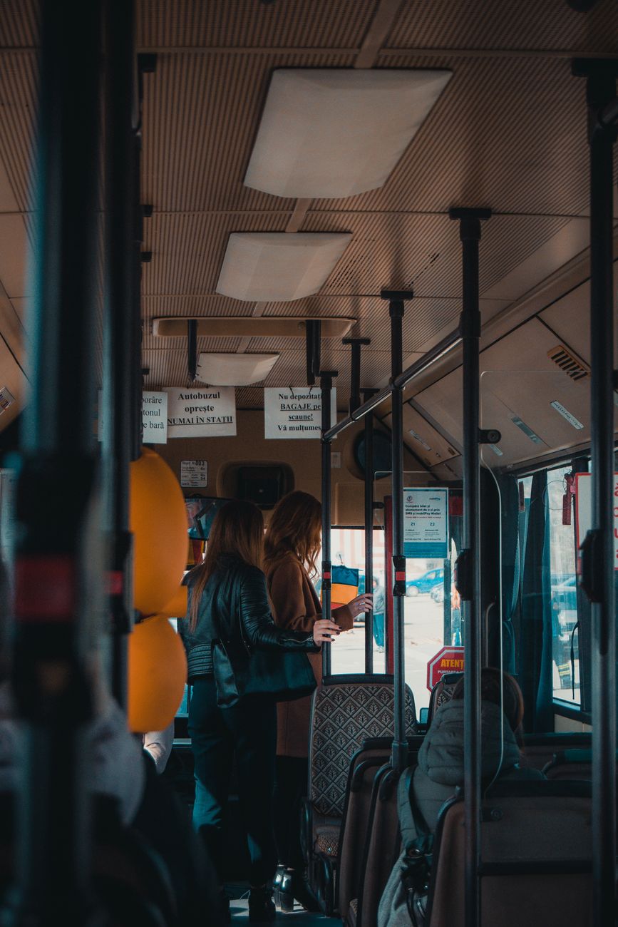 Interior shot of women commuting inside a city bus during the day, showcasing urban travel.