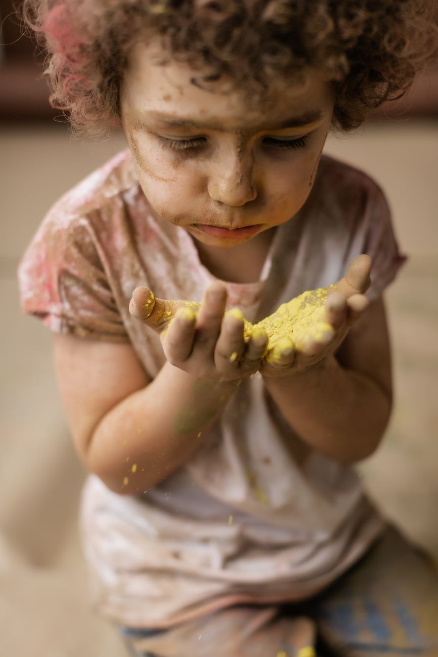 A young child joyfully holding colorful powder during the Holi festival celebration.