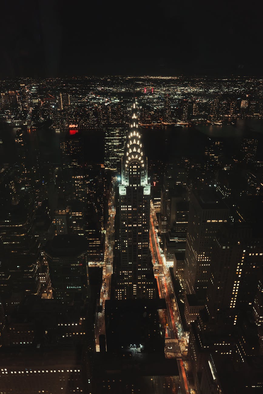Dramatic aerial shot of illuminated Chrysler Building amidst New York City skyline at night.