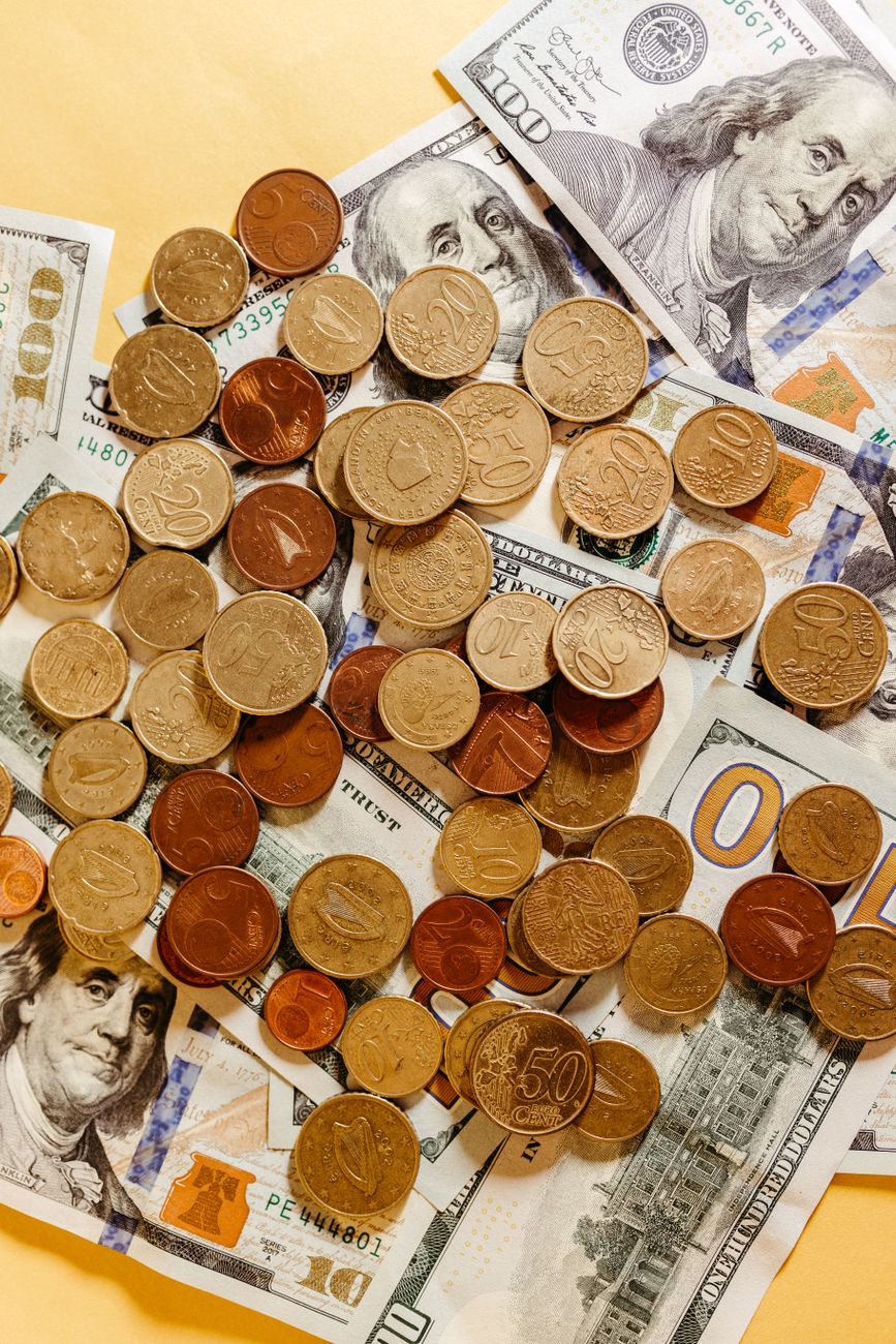 Mixed currency featuring US dollars and euro coins arranged in a flatlay.