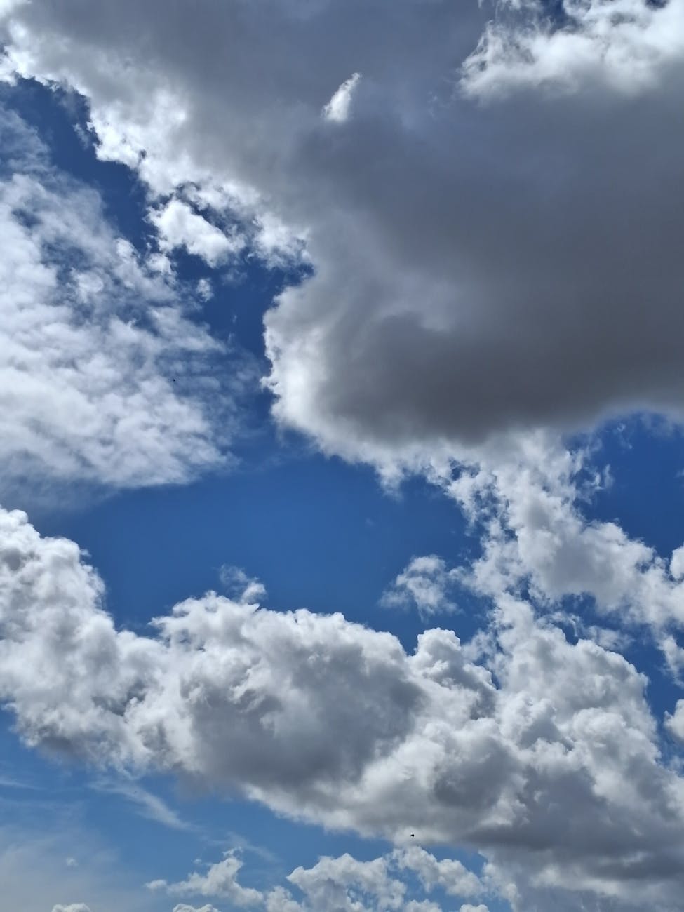 A captivating view of fluffy clouds against a vibrant blue sky, showcasing dramatic weather.