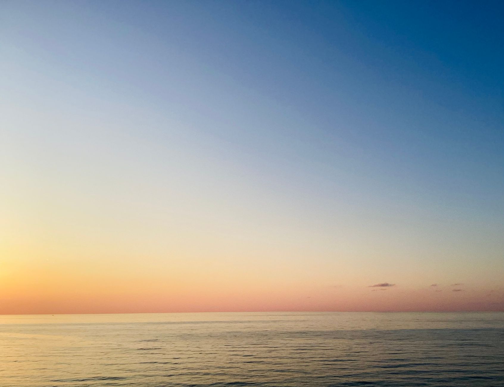 A serene sunset over a calm ocean, with vibrant pastel colors in the sky.