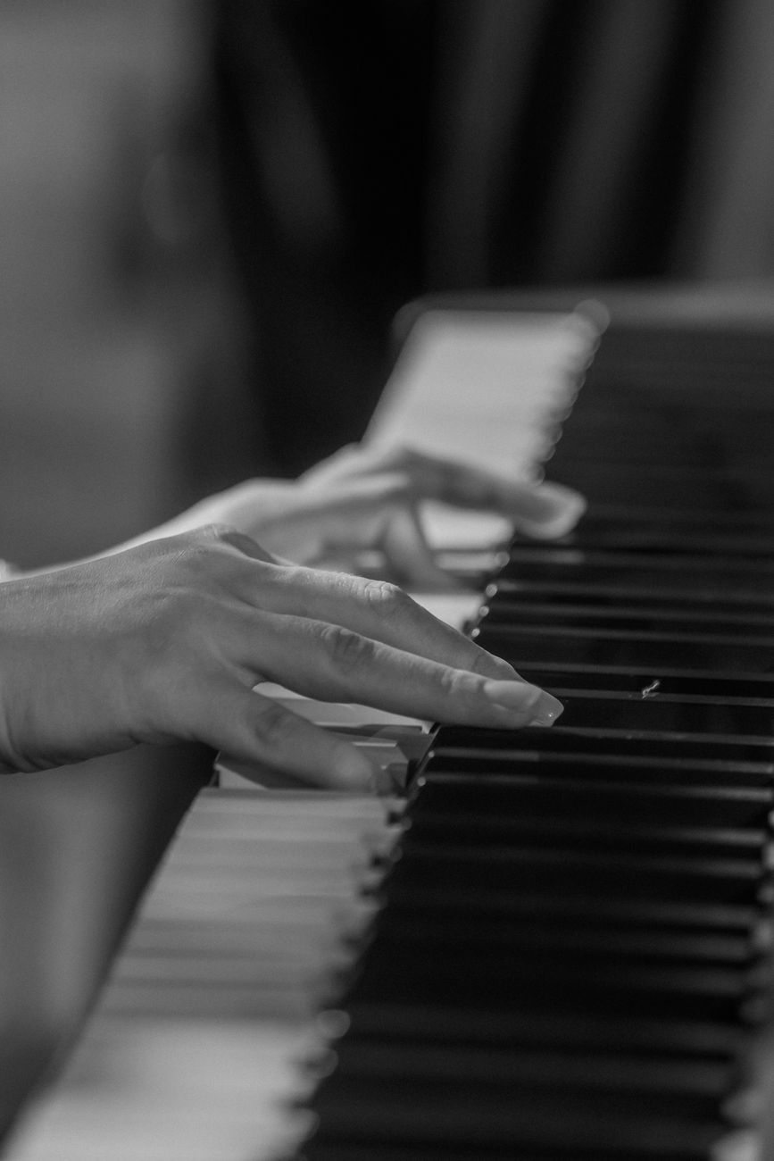Monochrome image of hands gracefully playing piano keys, evoking emotion and art.