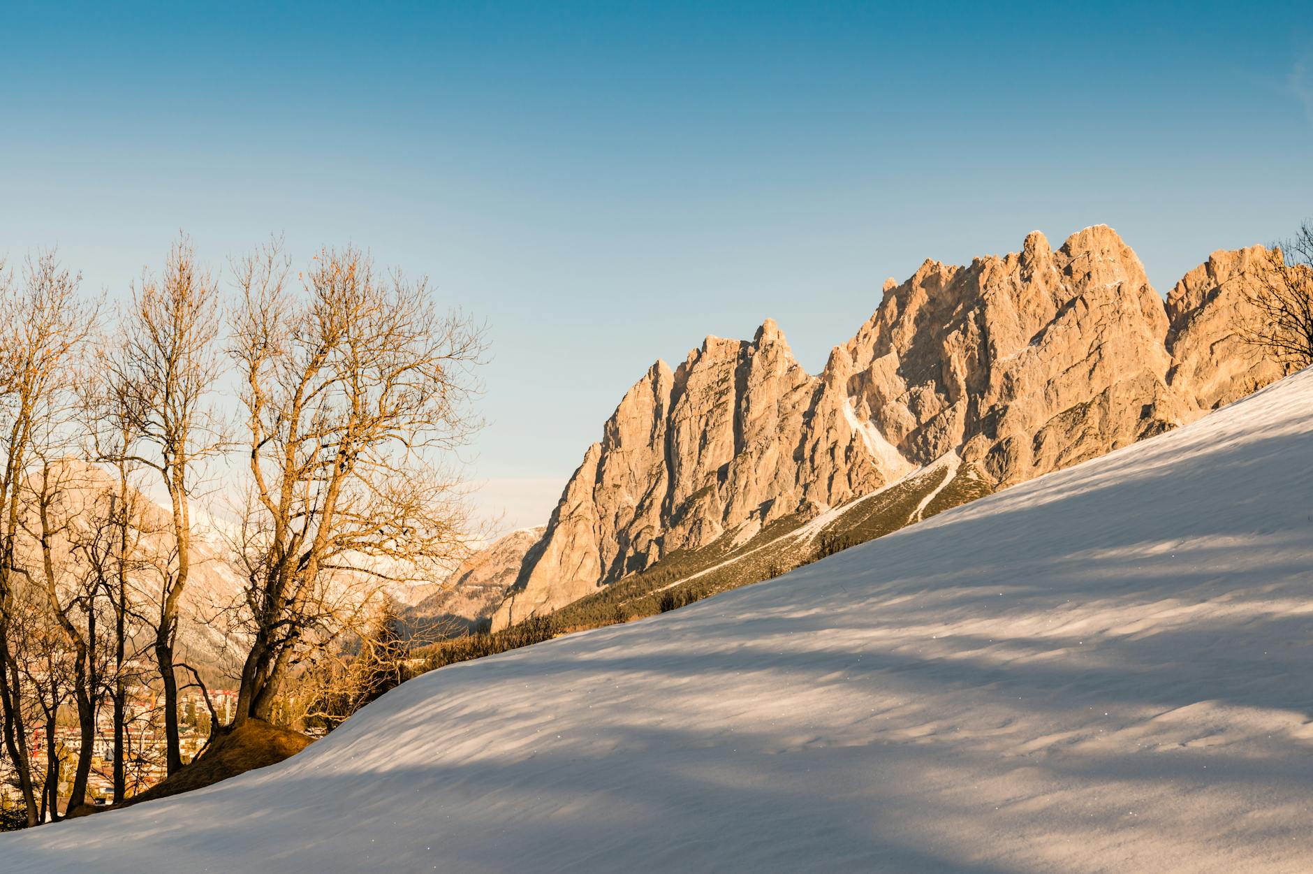 Beautiful snowy landscape of the Dolomites in Cortina d'Ampezzo, Italy, showcasing bare trees and rocky peaks.