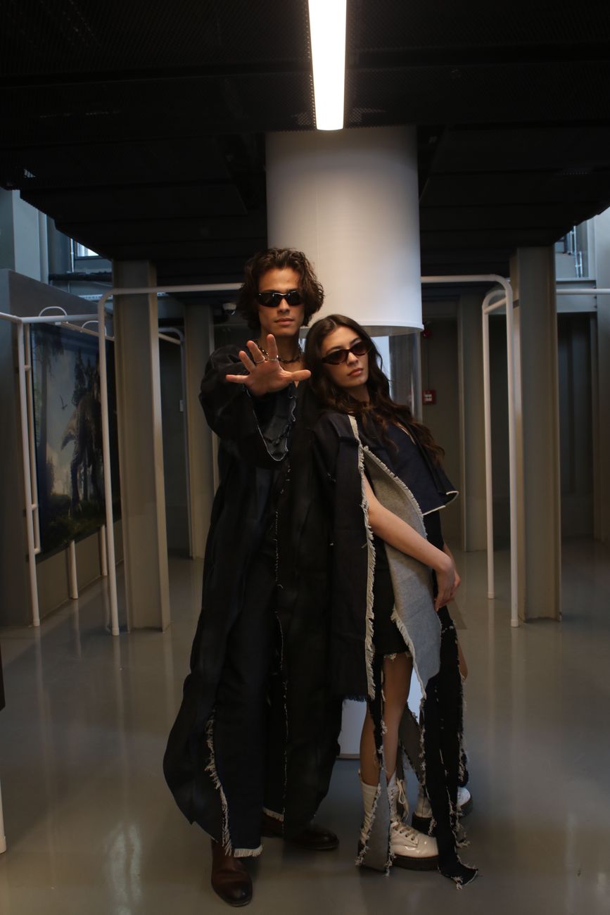Trendy man and woman with sunglasses posing in a modern art gallery. Fashionable and edgy.