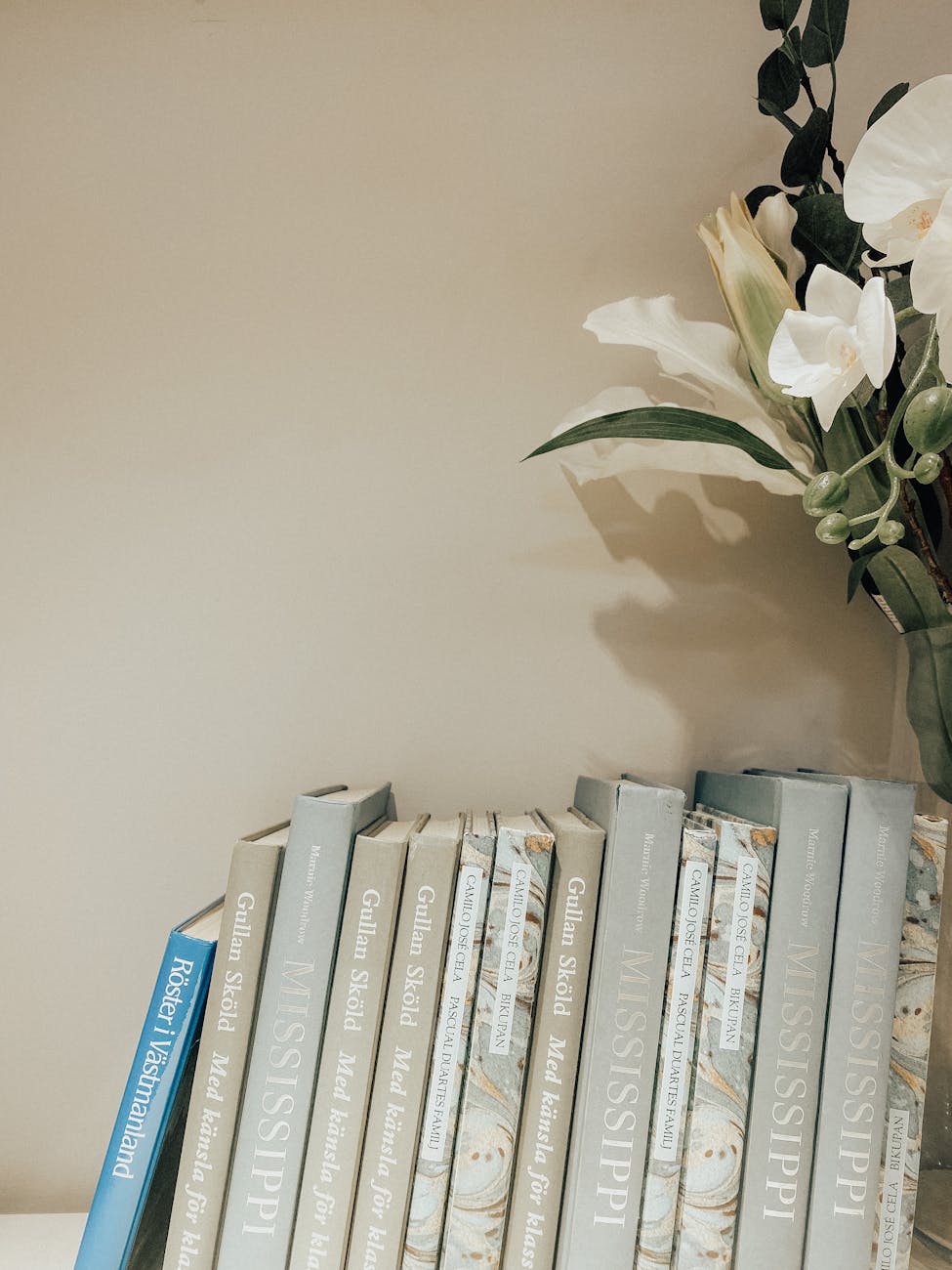 A stylish bookshelf arrangement with books and white flowers in a modern decor setting.