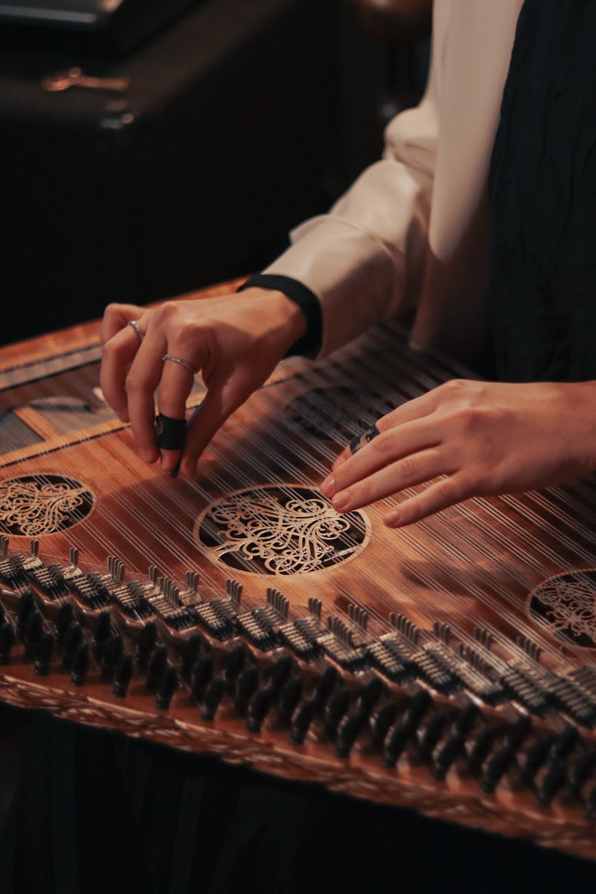 An artistic close-up of hands tuning a traditional kanun string instrument, highlighting intricate details.