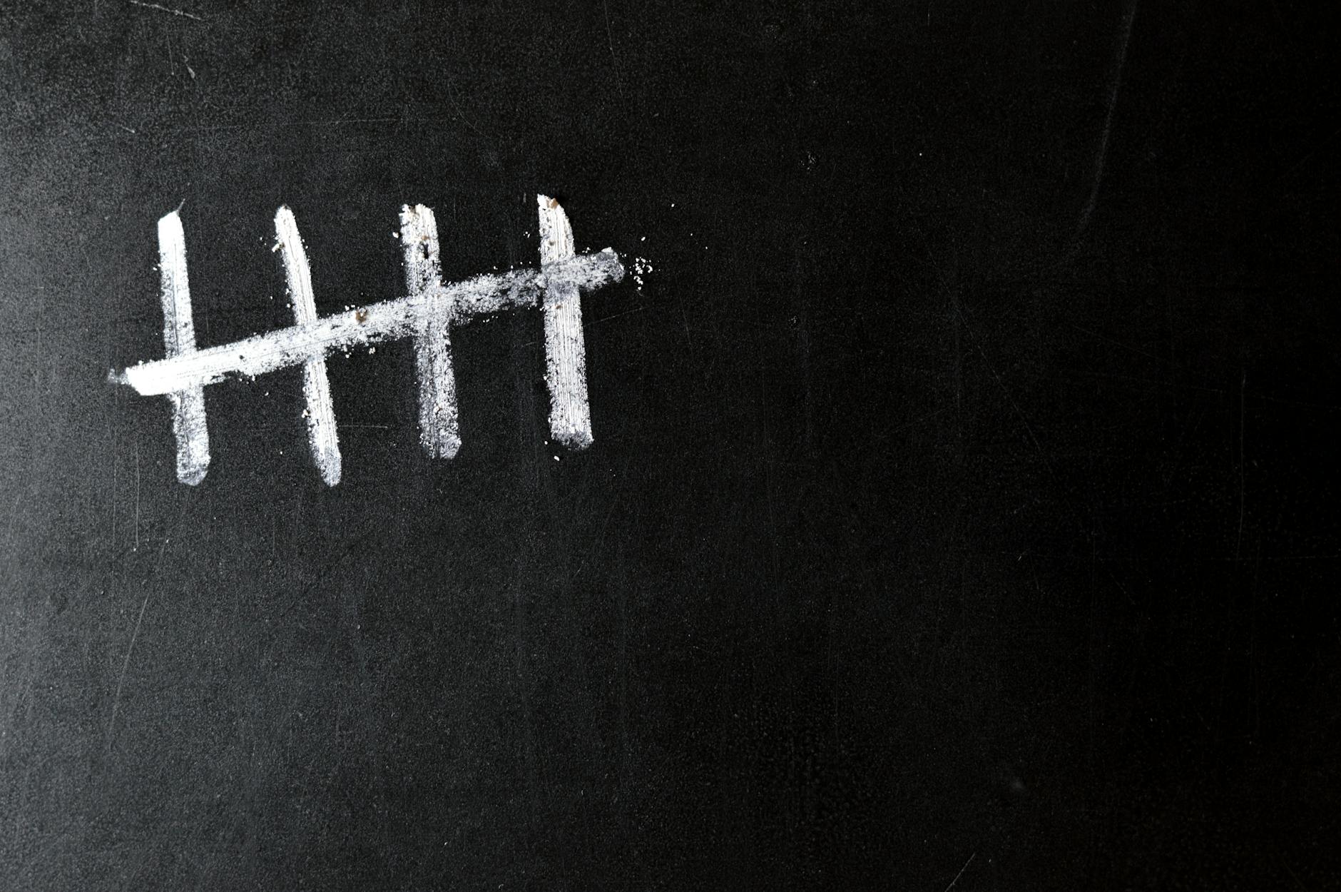 Five chalk tally marks on a black chalkboard background.