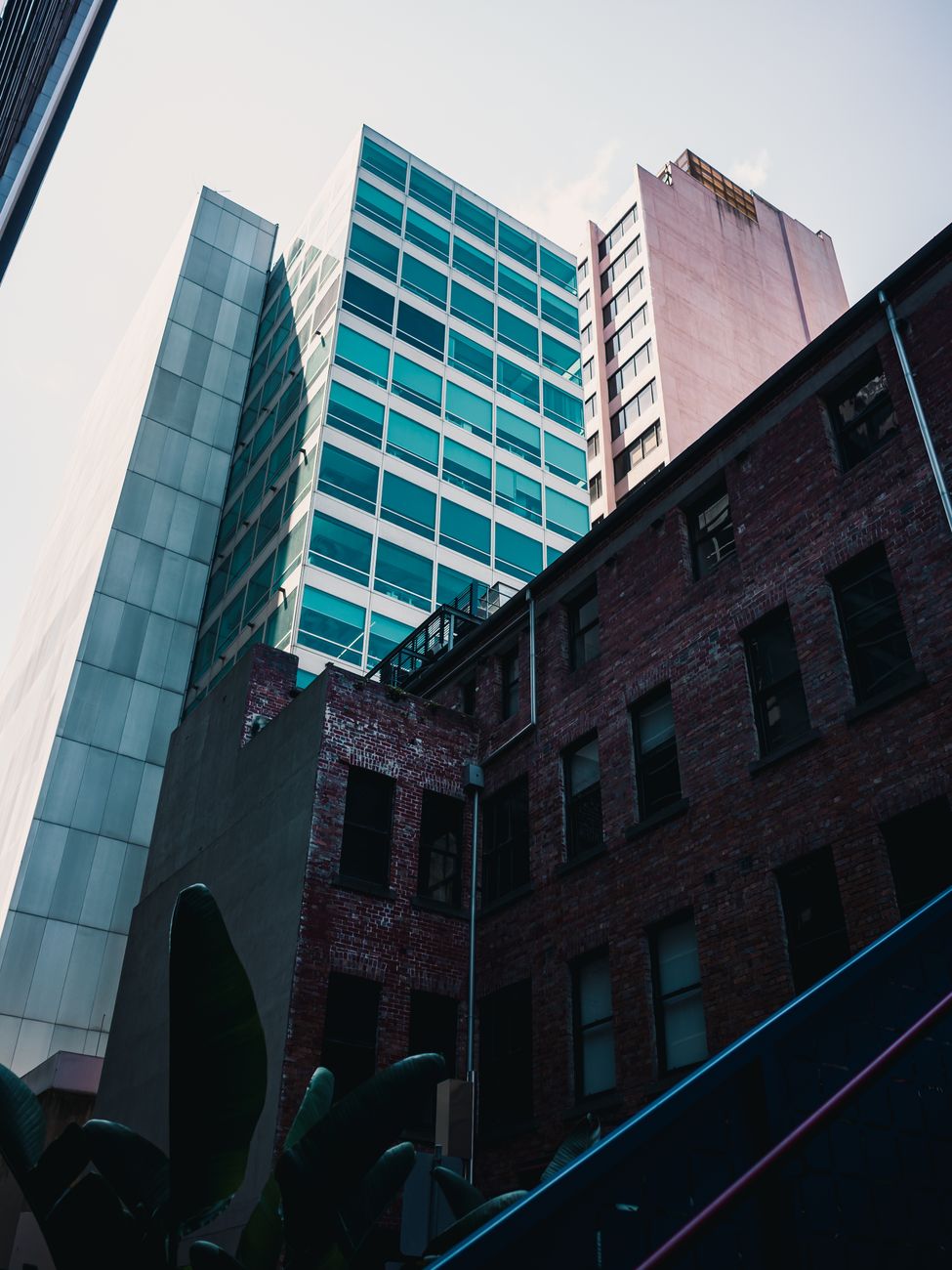 Contrast between modern glass skyscrapers and historic brick buildings in an urban setting.