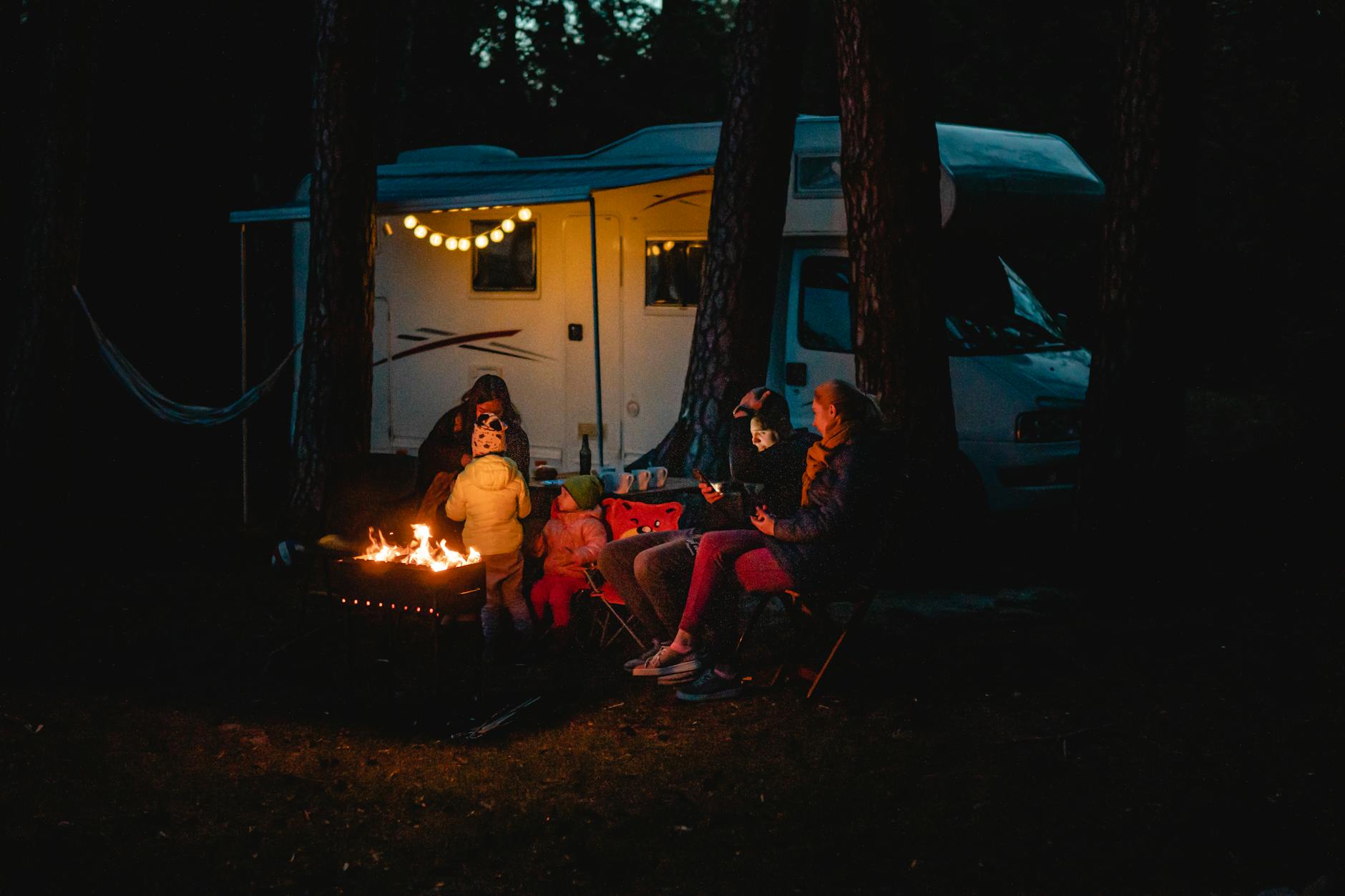 Family enjoying a warm night by the campfire beside their campervan in Lithuania.