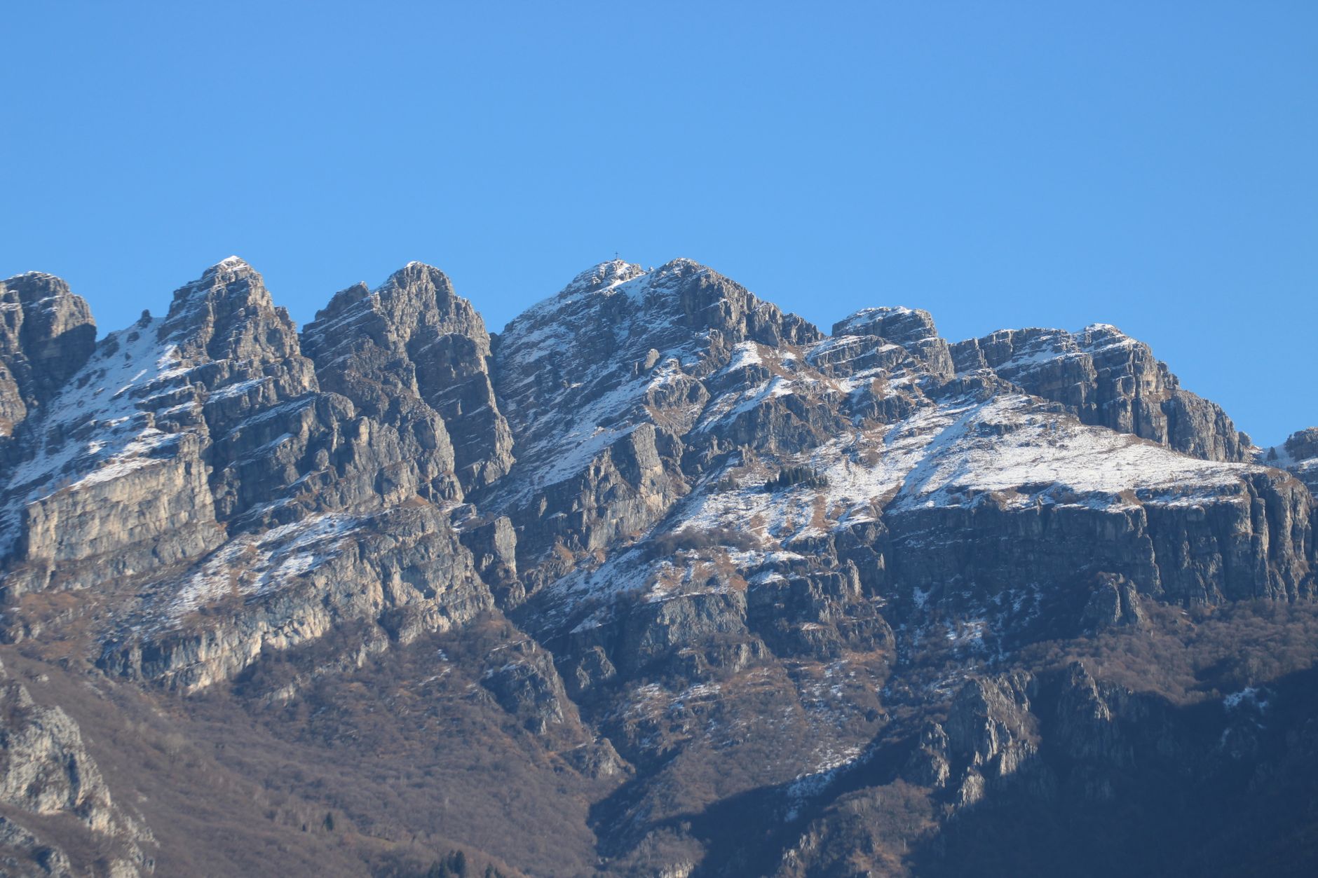 Breathtaking view of snow-covered mountain peaks in Lombardy, Italy under a clear blue sky.