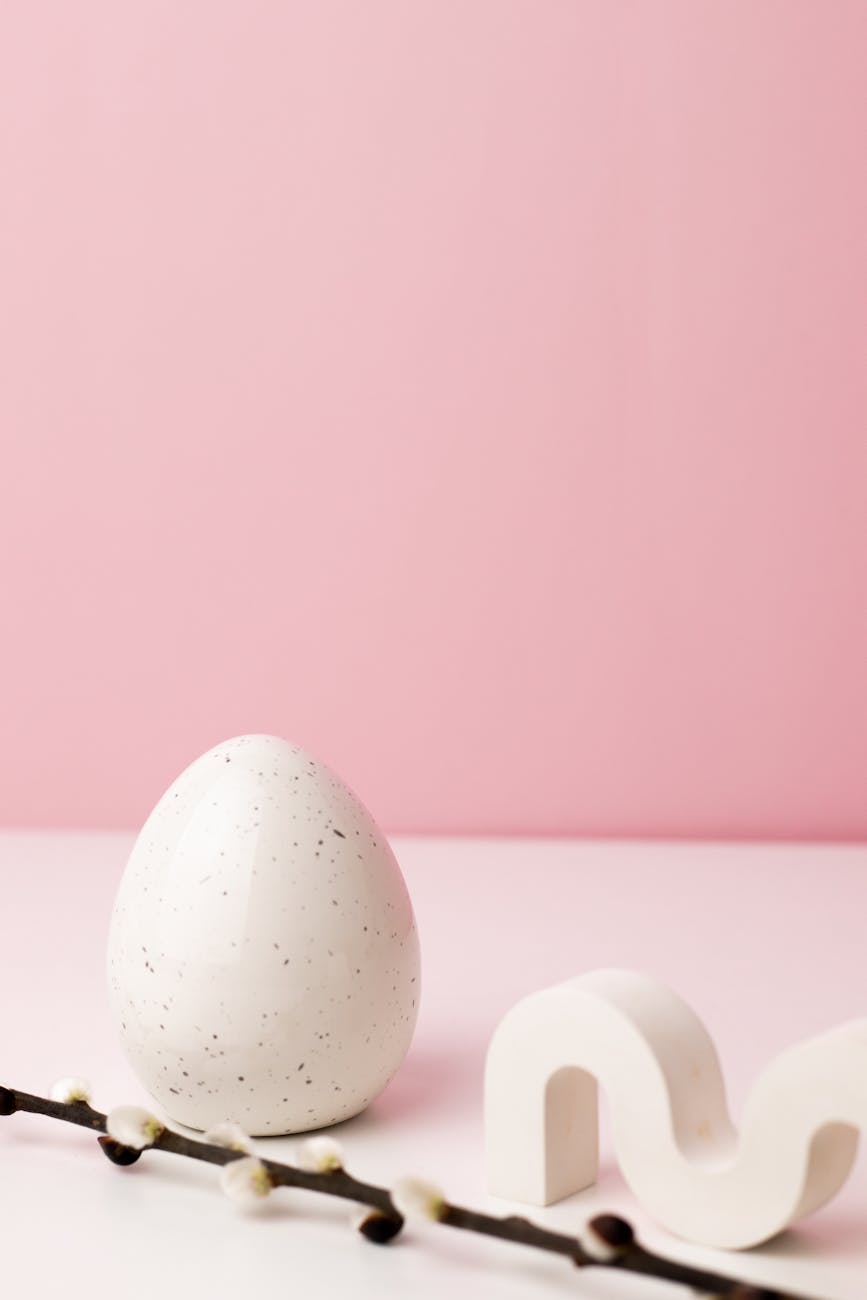 Minimalist white egg with speckles on a pink background, perfect for Easter themes.