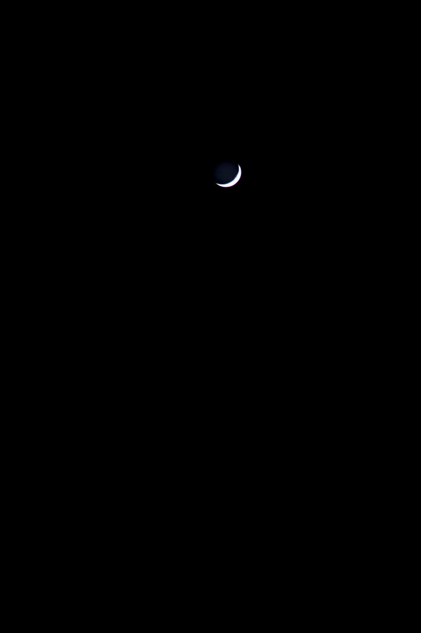 A serene crescent moon shining against a vast dark night sky, creating a peaceful and tranquil scene.