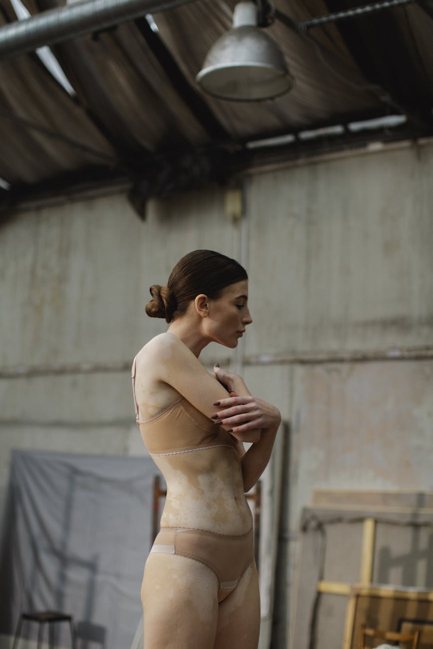 A woman in lingerie poses gracefully in an industrial space, highlighting beauty and empowerment.