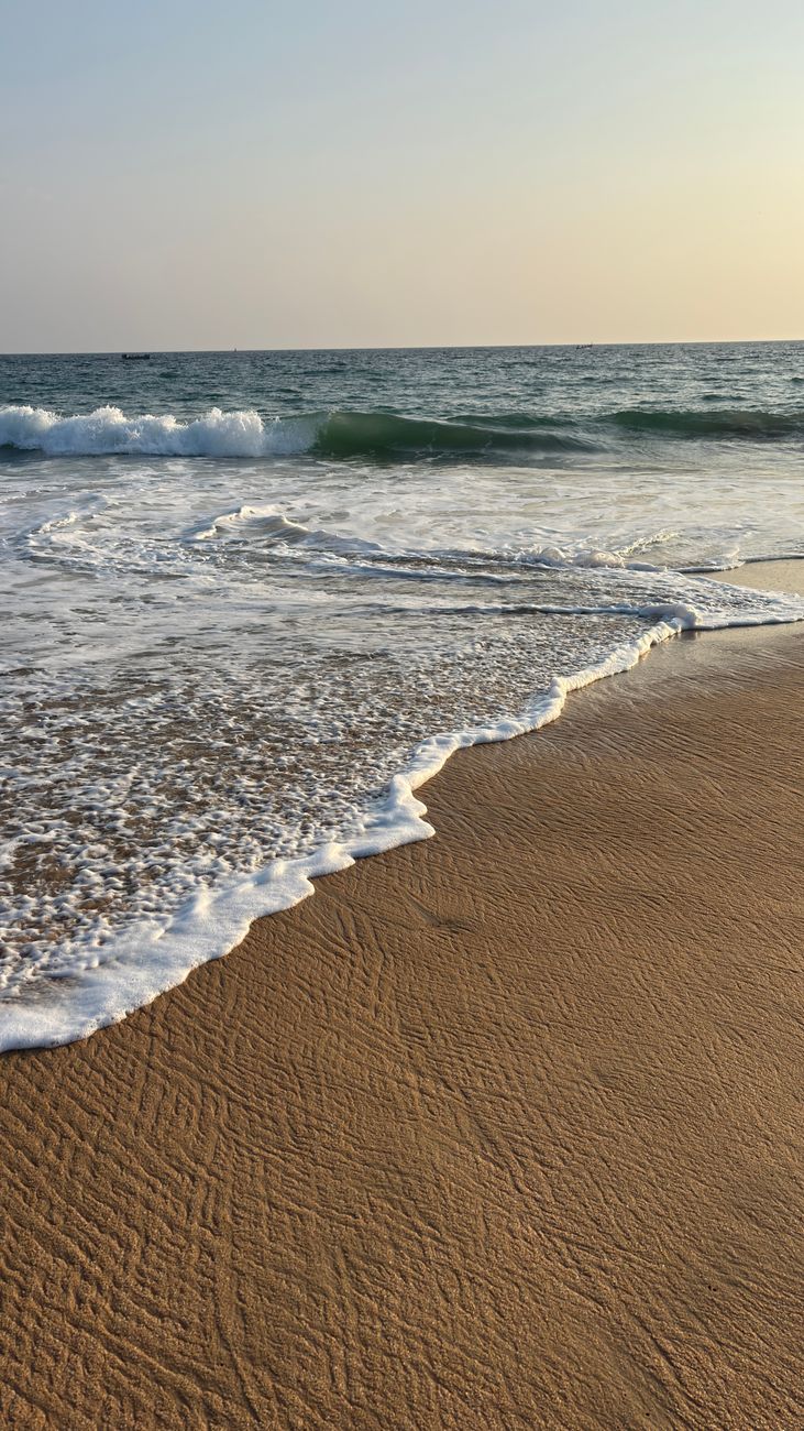 Peaceful beach scene at sunset with soft waves and golden sand.