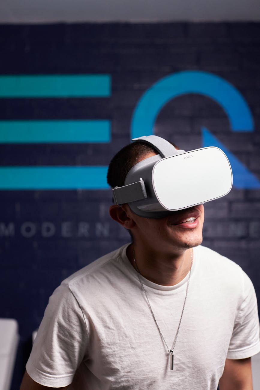 A man wearing VR goggles smiles while engaging with virtual reality technology indoors.