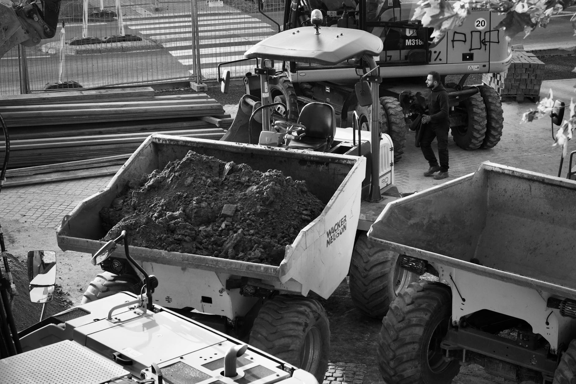 Black and white image of a construction site with machinery and a worker.