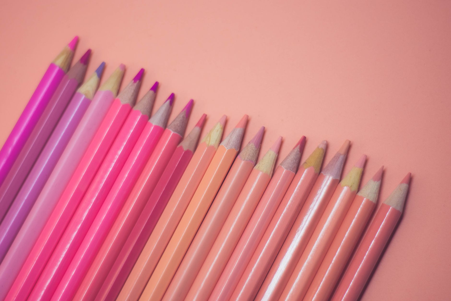 A collection of pink and pastel colored pencils laid on a soft pink background, offering a creative and artistic vibe.