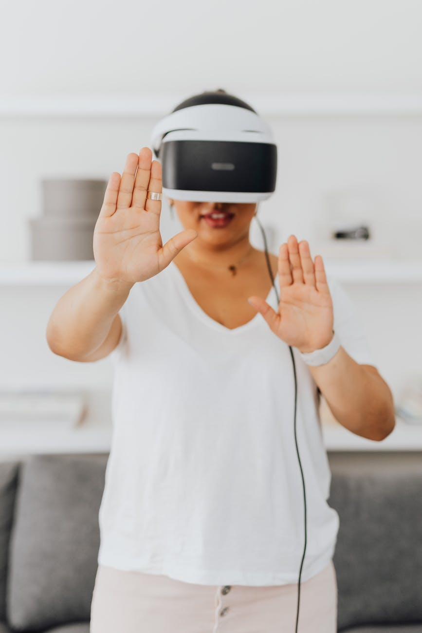 Adult woman using VR headset indoors, experiencing virtual reality with interactive gestures.