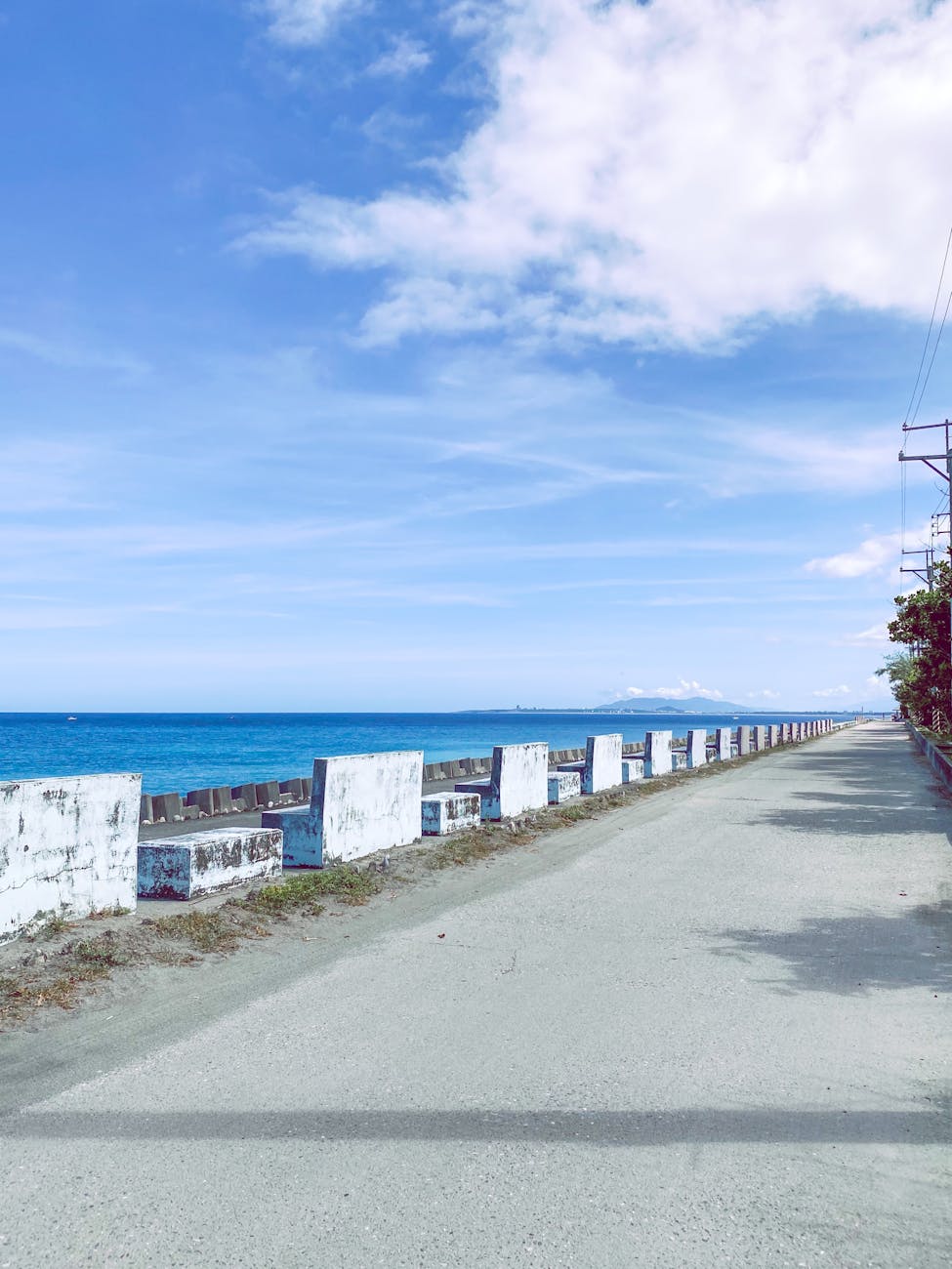 Scenic empty coastal road alongside a vibrant blue ocean on a clear summer day.