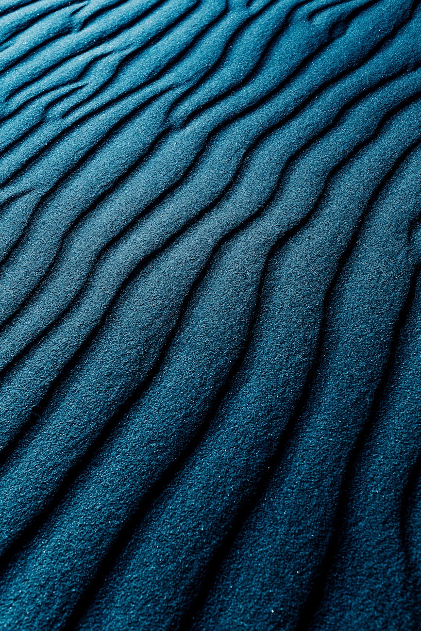 Close-up of dark blue textured sand dunes with a wavy pattern, perfect for backgrounds.