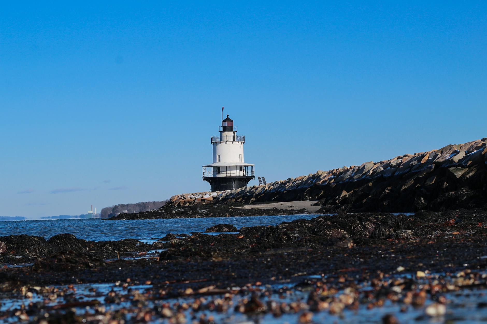 Iconic Spring Point Ledge Lighthouse on a clear blue day in Portland, Maine.