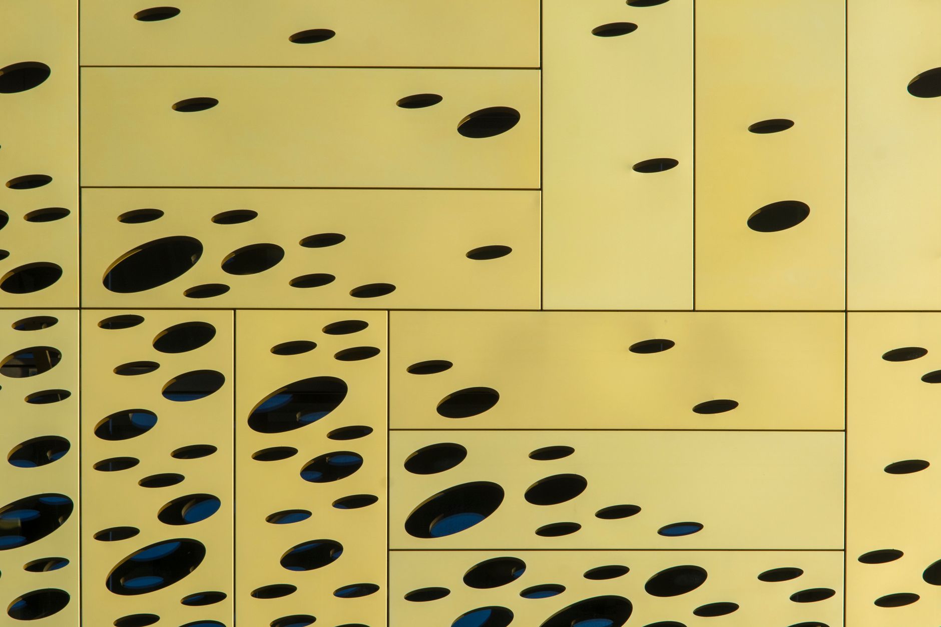 Close-up of a modern yellow wall with unique circular cutouts creating an abstract design.