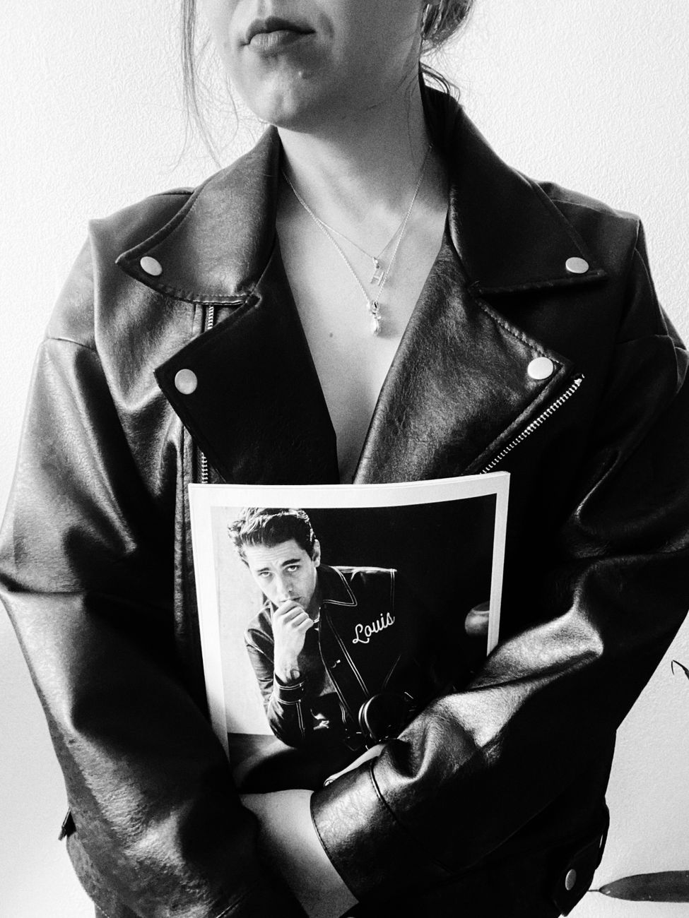 Monochrome image of a person holding a vintage portrait, wearing a leather jacket.