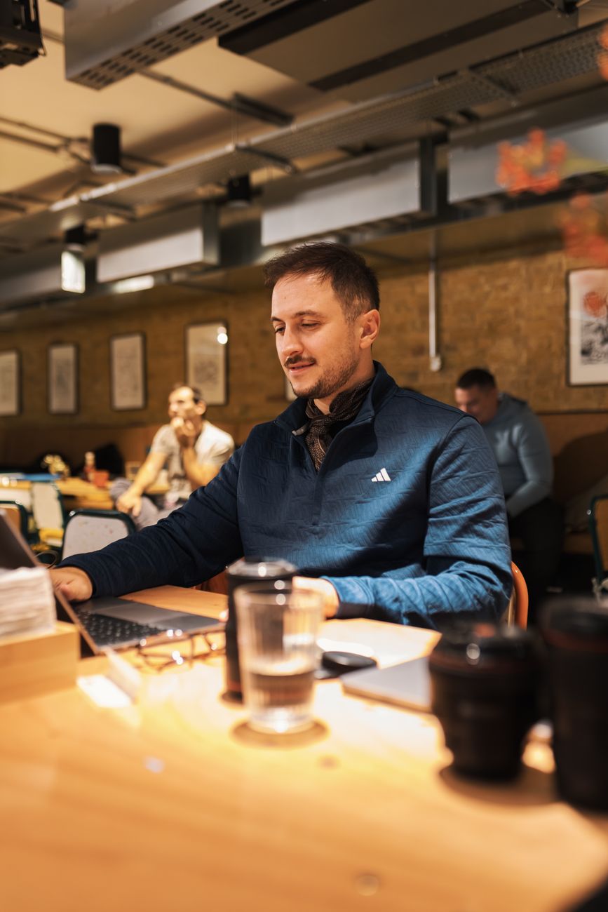 A young man focused on work in a modern café, showcasing a casual work environment.