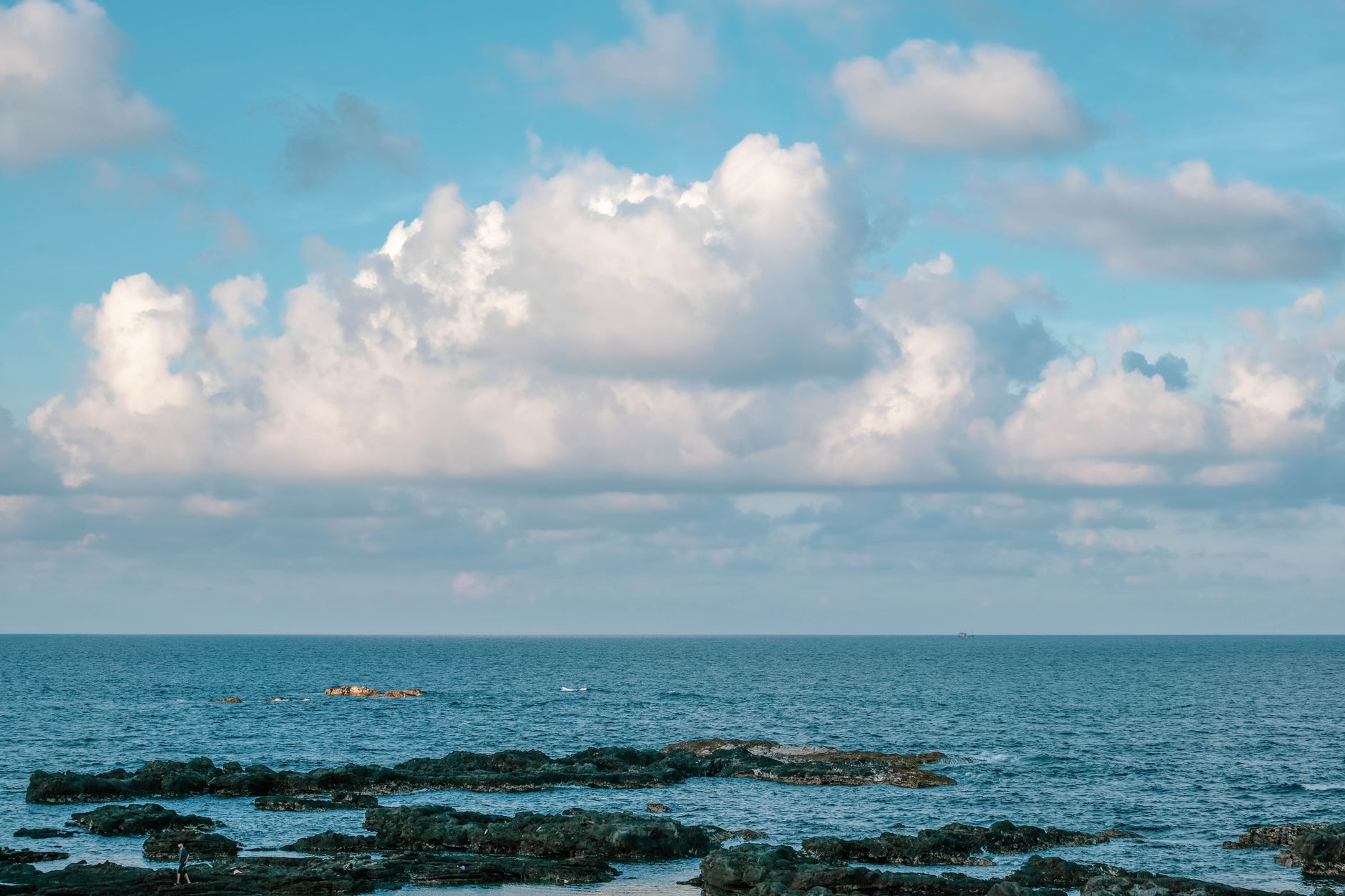 Peaceful coastal scene featuring rocks and sea under a bright blue sky in Bình Thuận, Vietnam.