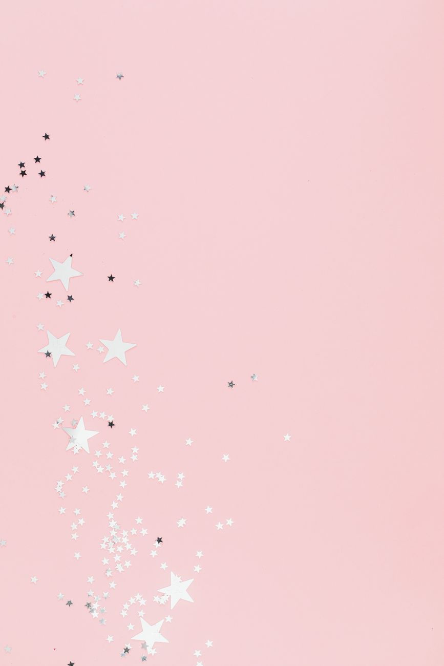 Soft pink pastel background with scattered star-shaped confetti, perfect for festive designs.