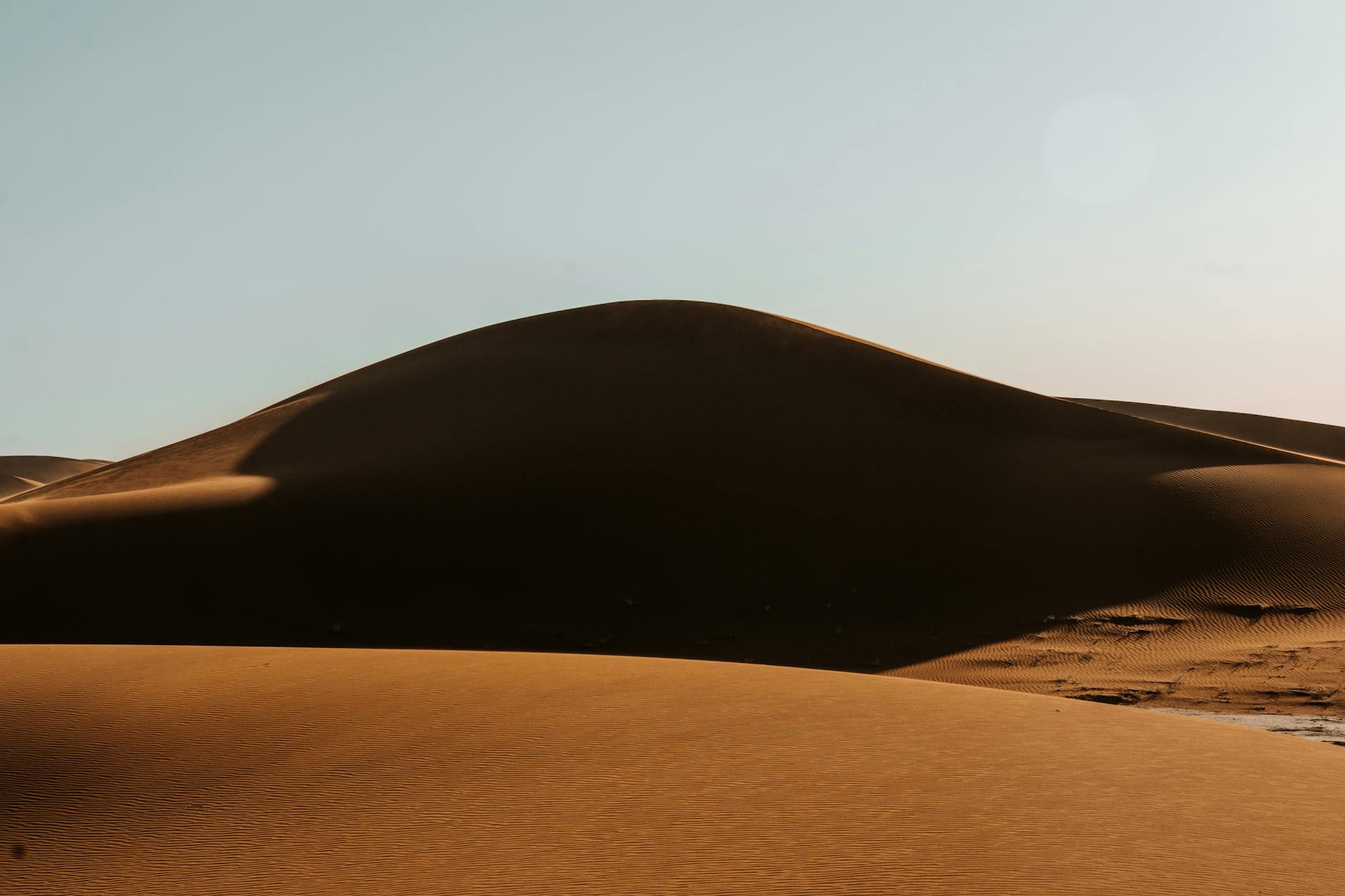 Captivating view of sand dunes in Sahara Desert under a clear sky in Morocco.