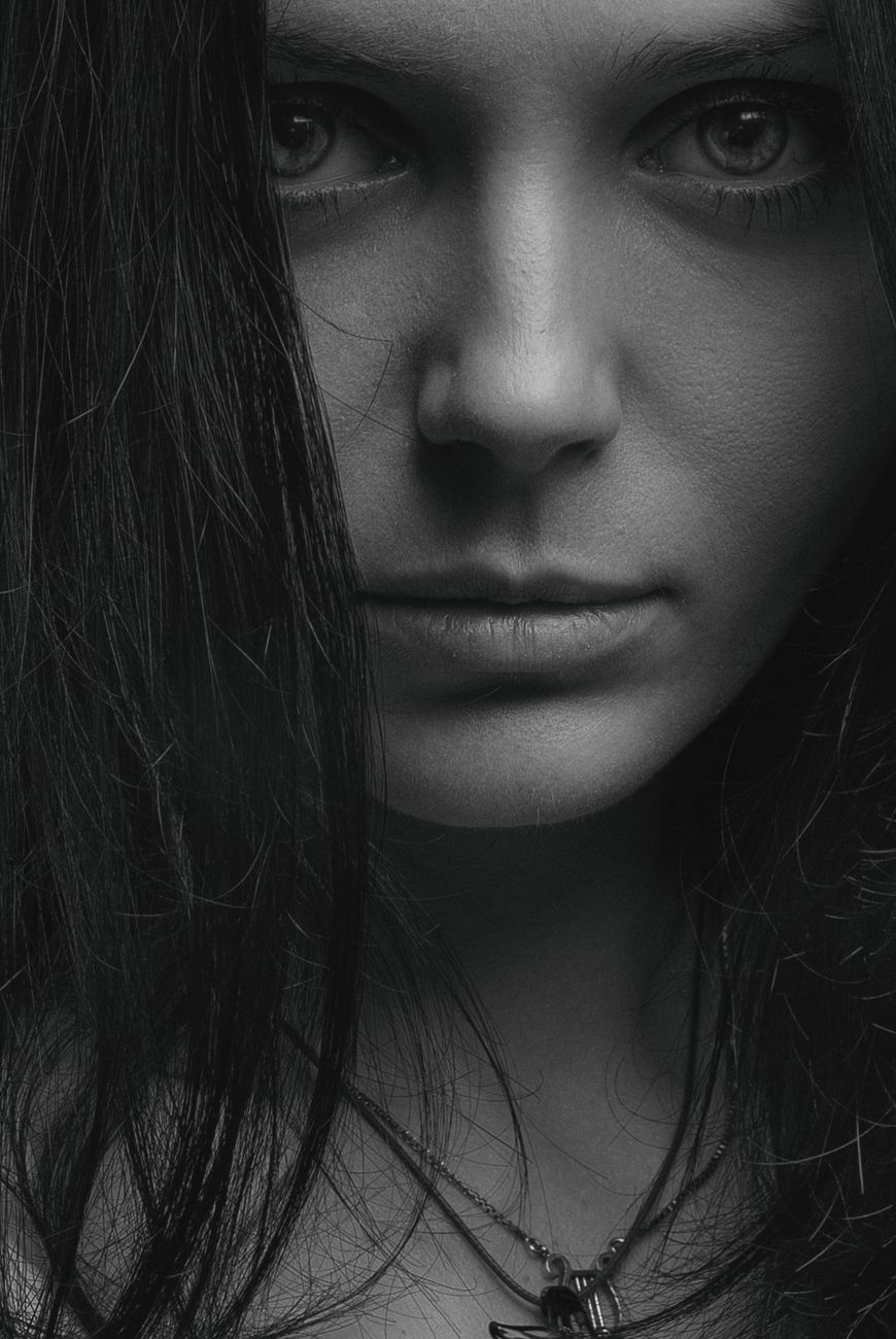 Close-up black and white portrait of a woman with intense gaze, creating a moody atmosphere.