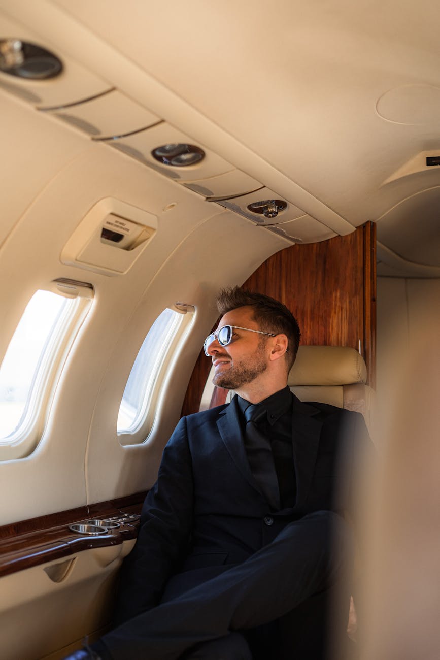 A man in a suit and sunglasses enjoys a luxurious flight in a private jet.