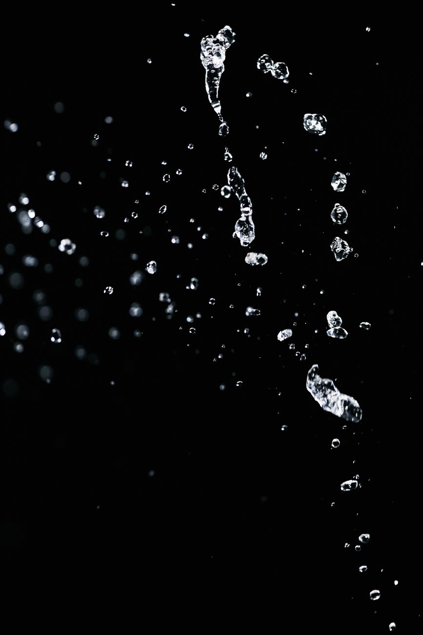 Dynamic capture of water droplets suspended against a dark backdrop, showcasing fluid motion.