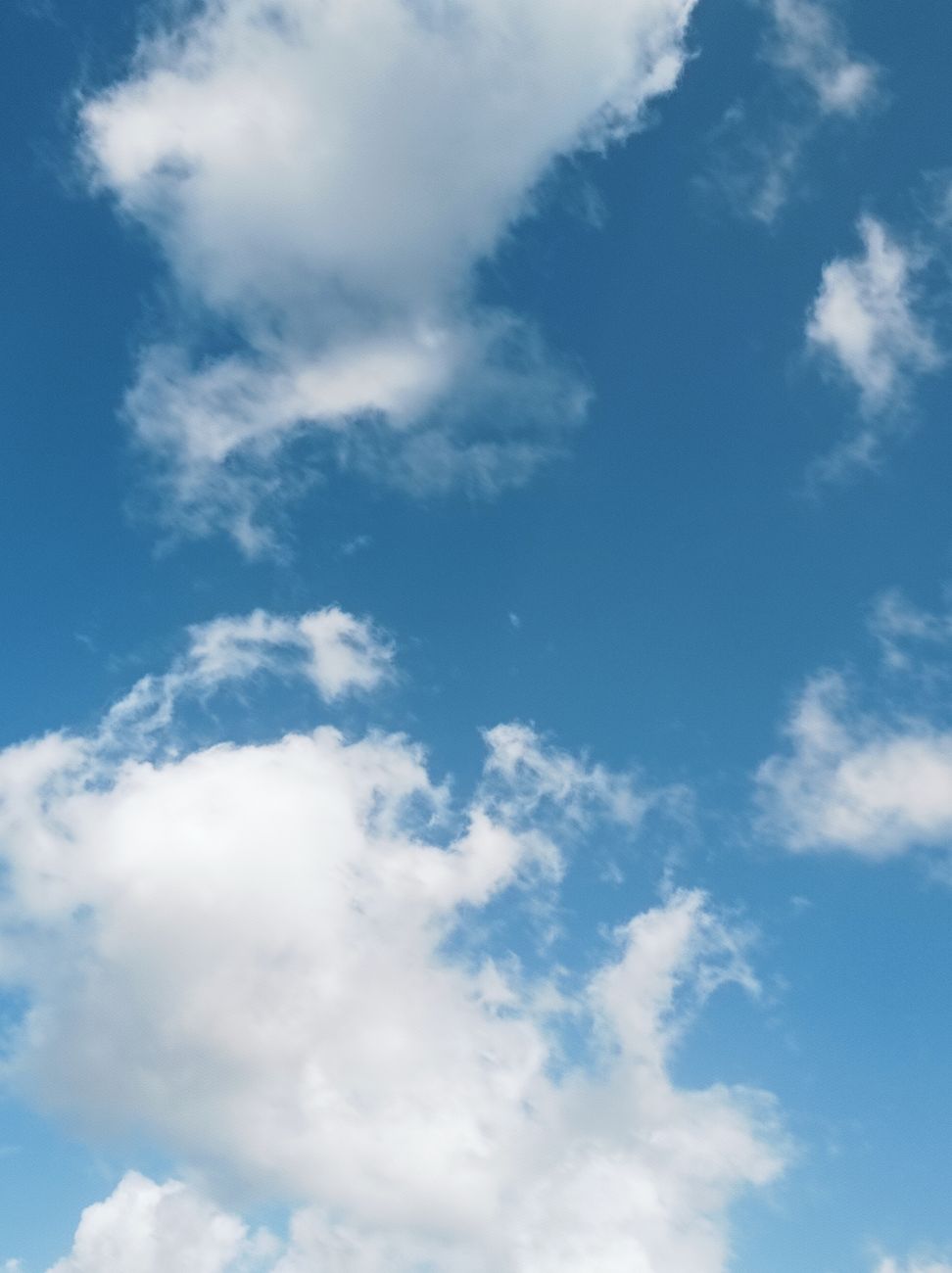 Vibrant blue sky filled with fluffy white clouds on a sunny day.