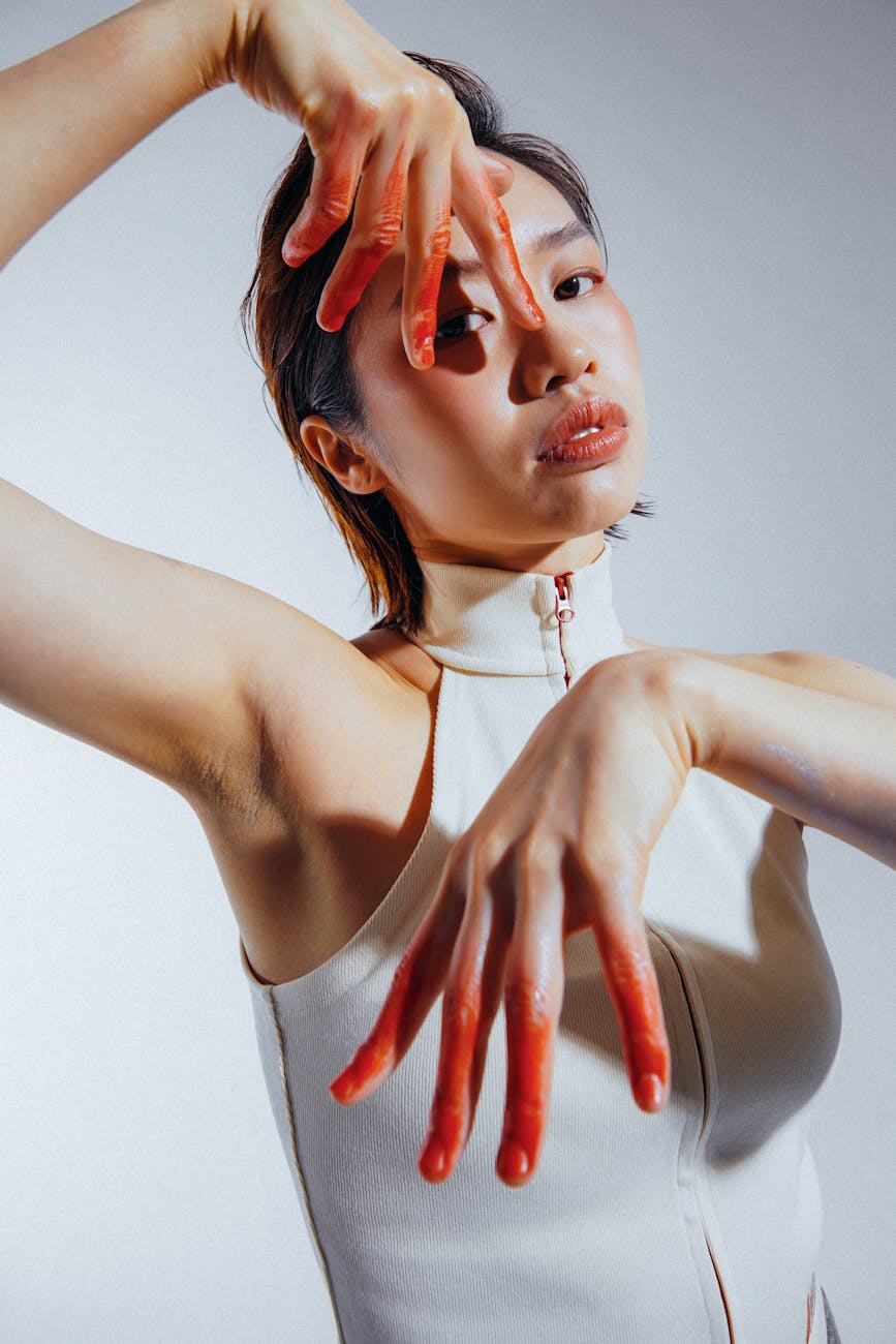 Artistic fashion portrait of a woman in a studio with painted fingers, exploring unique beauty concepts.