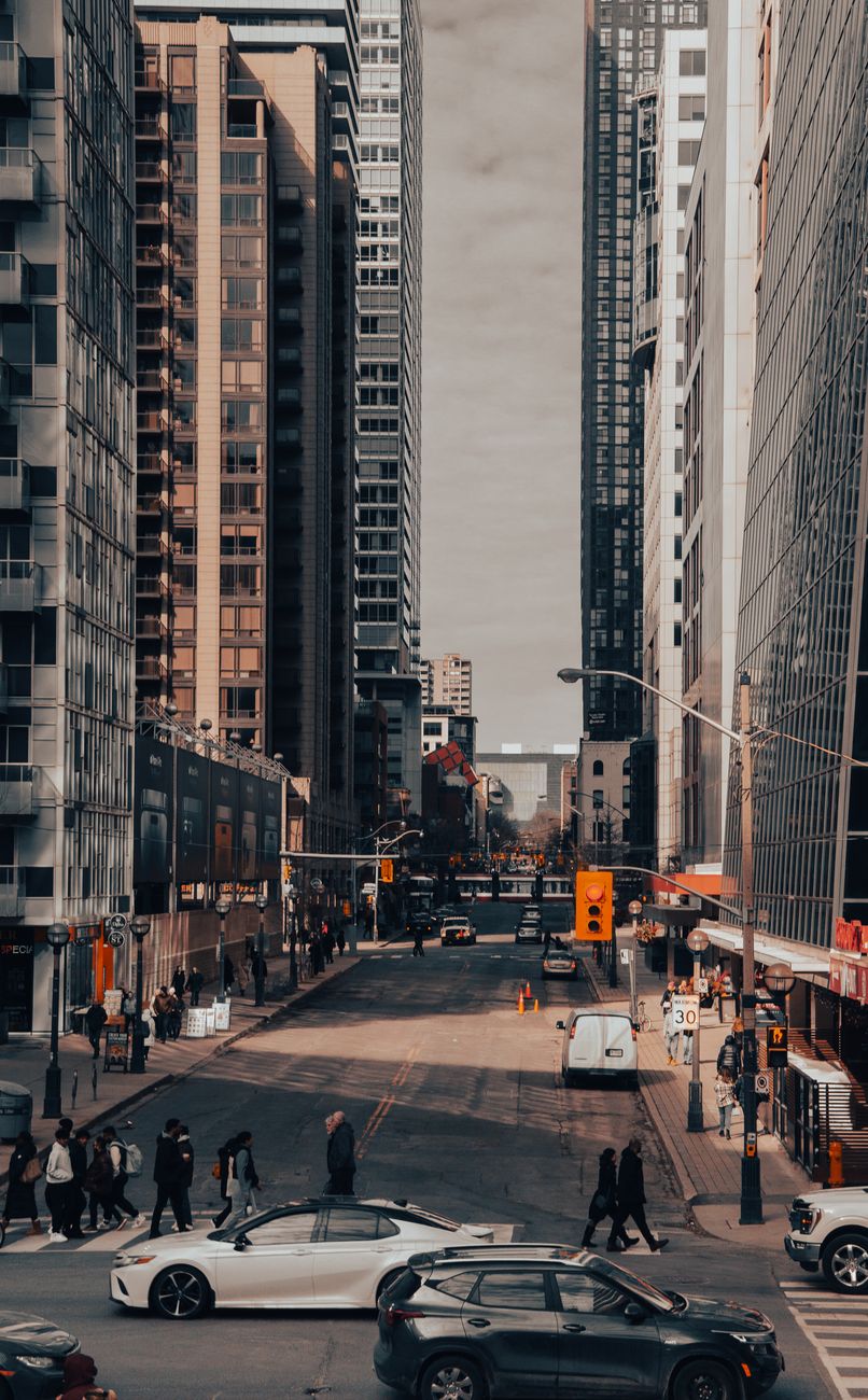 Vibrant city street with skyscrapers, cars, and pedestrians in a bustling urban setting.