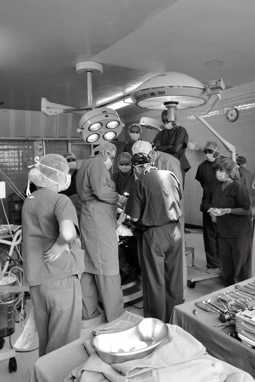 Surgical team performing a medical procedure in a busy operating room. Medical teamwork and precision.