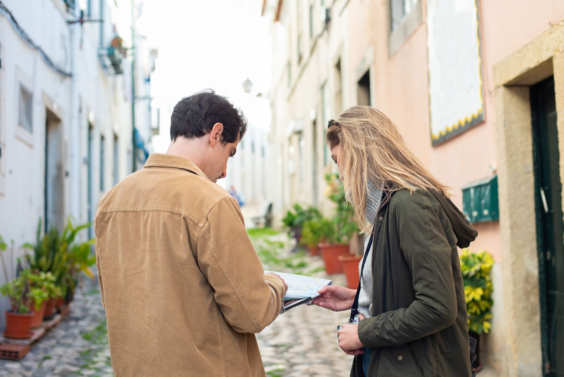 Two travelers exploring a charming European street, using a map for navigation.