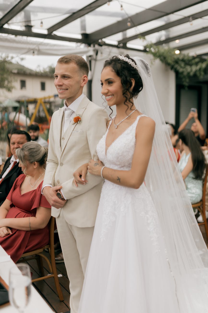 Bride and groom standing together during an elegant outdoor wedding ceremony with guests seated nearby.