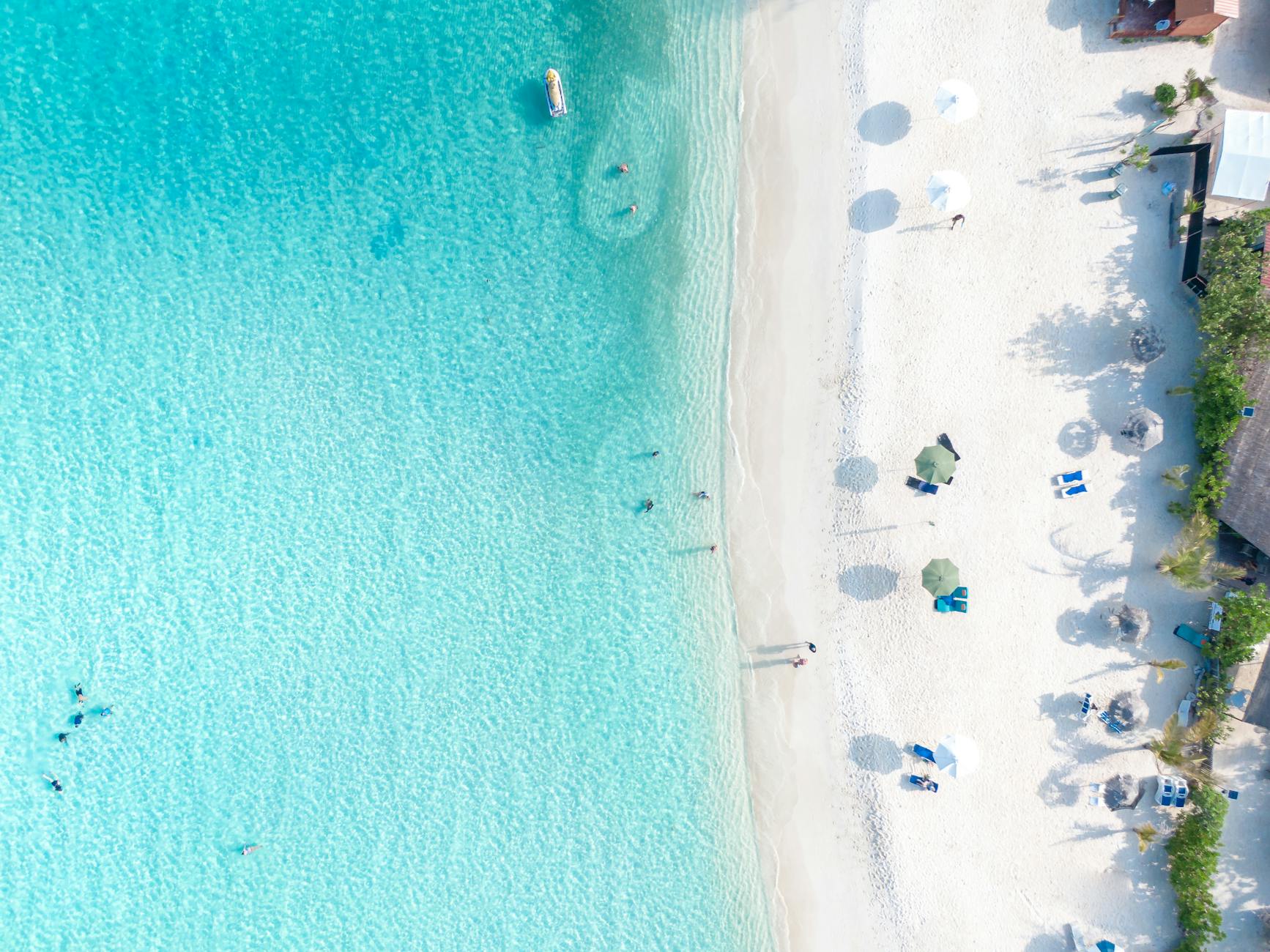Stunning aerial photo of a tropical beach with turquoise water and white sand, capturing relaxation and natural beauty.