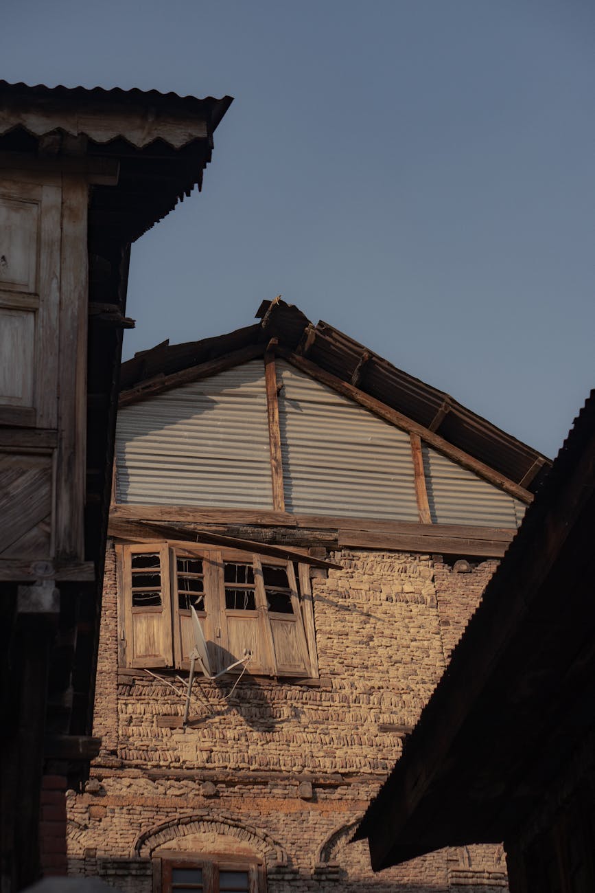 Rustic building with wooden accents and a dilapidated window under clear sky.