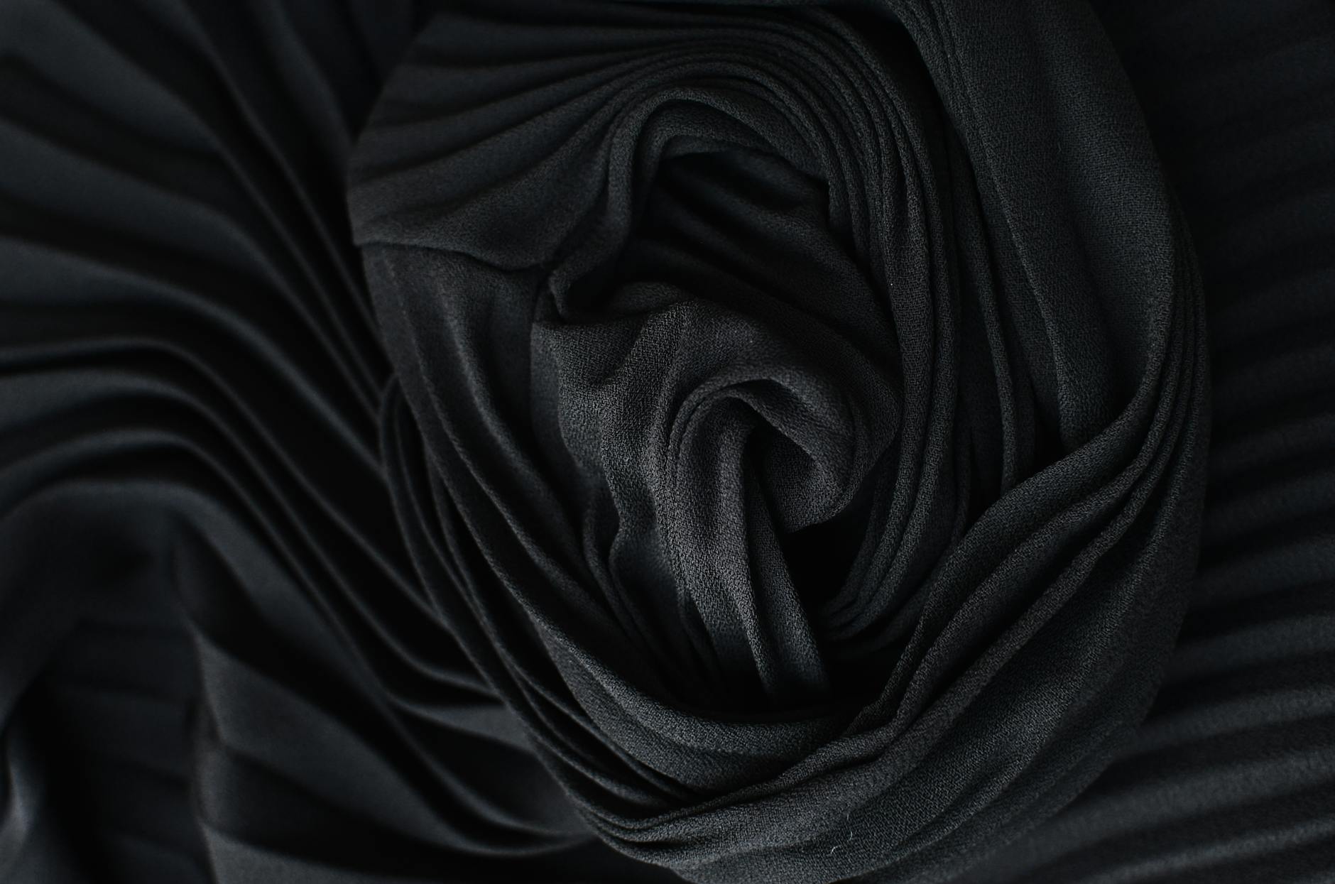 Detailed close-up of black pleated fabric showing intricate folds and texture.
