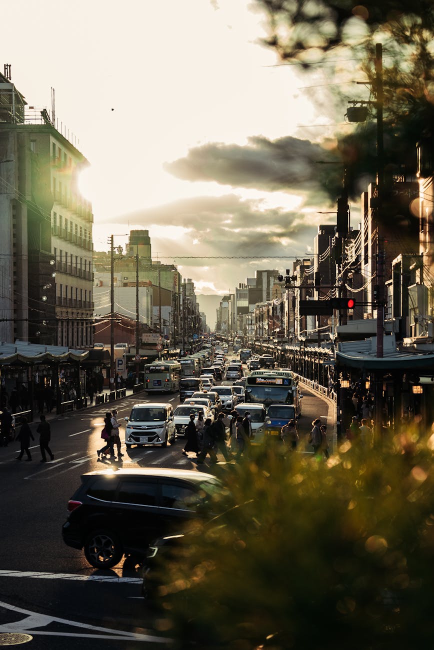 Bustling Kyoto streetscape at sunset, capturing urban life with traffic and pedestrians.